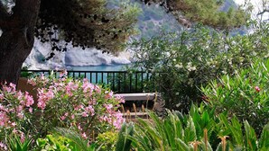 A garden with a bench, various plants, and a mountainous backdrop. - Baia Delle Zagare - Handwritten Collection (Mattinata)
