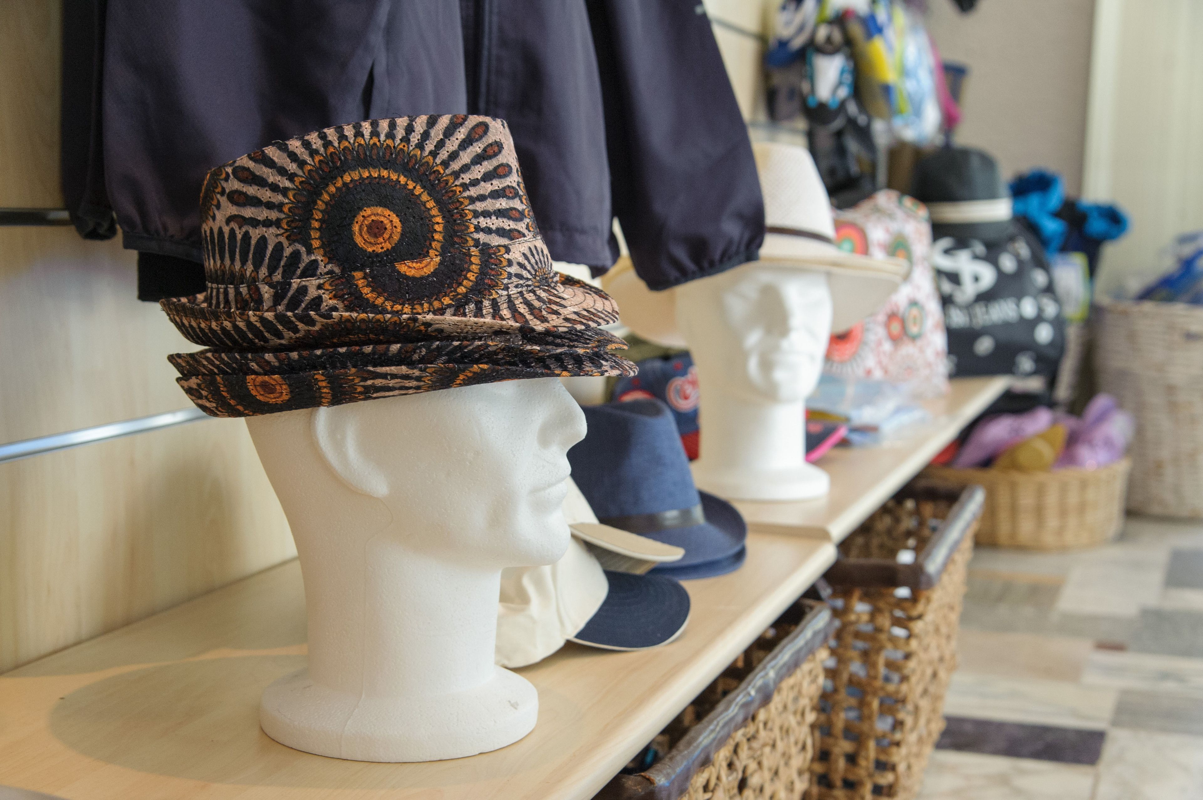 Hoeden tentoongesteld op mannequins in een winkel.