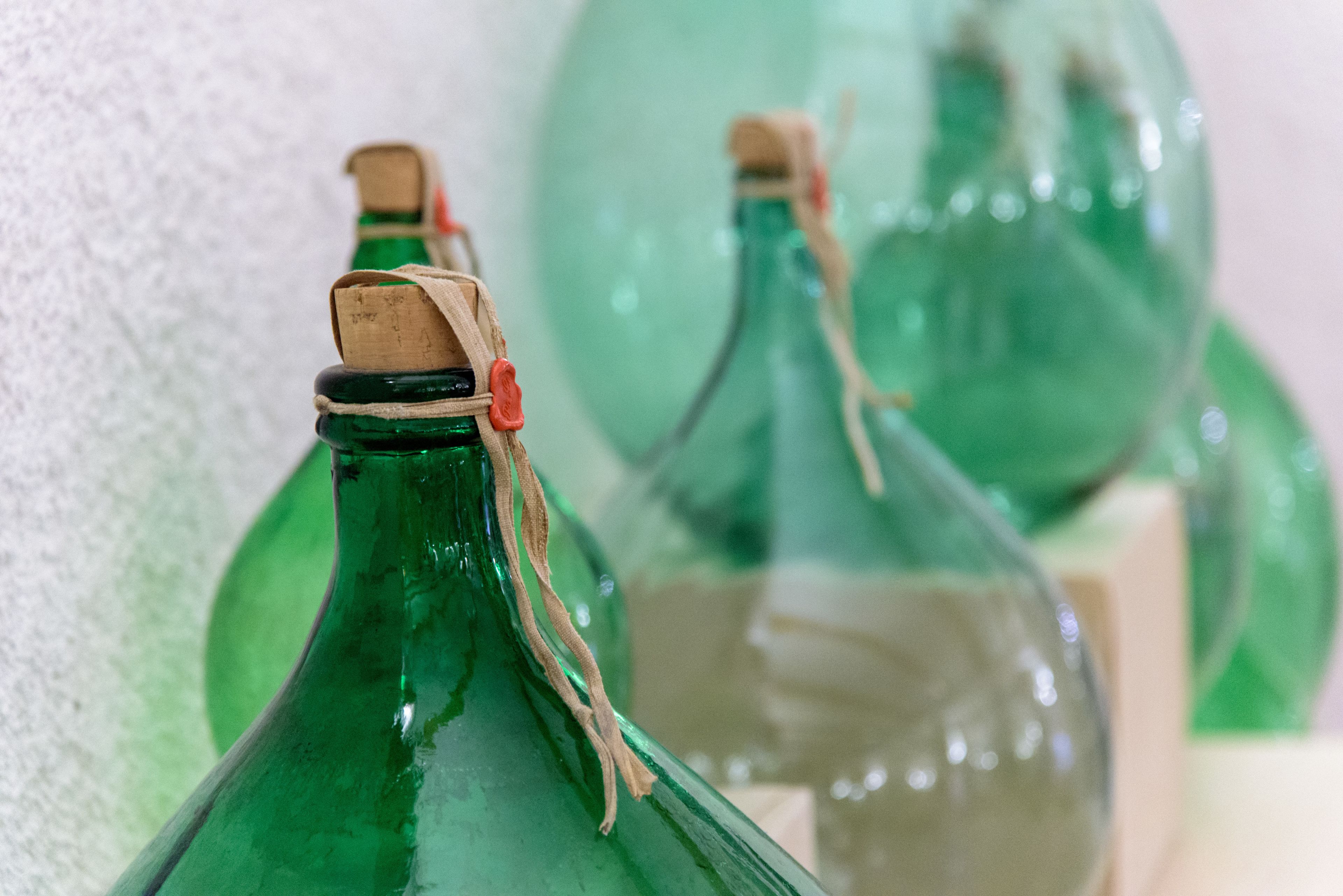 A close-up of green glass bottles with cork stoppers tied with twine, likely used for storage or decoration.