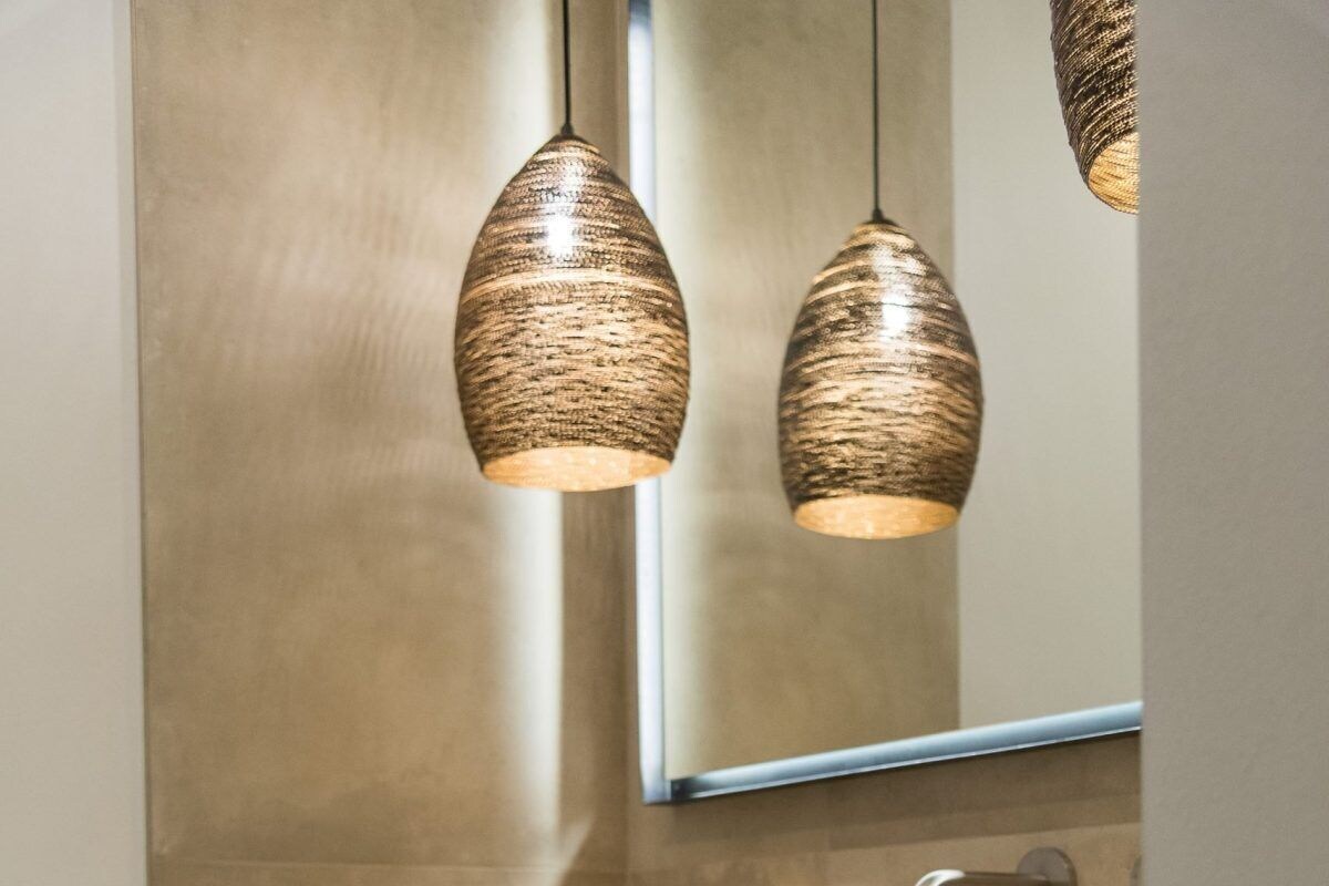 Een moderne badkamer met een grote spiegel, een handdoekhouder, een wastafel met een zakdoosje en een decoratieve mand.