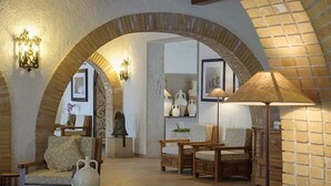 A cozy interior with a brick archway, wooden furniture, and decorative items. - Baia Delle Zagare - Handwritten Collection (Mattinata)