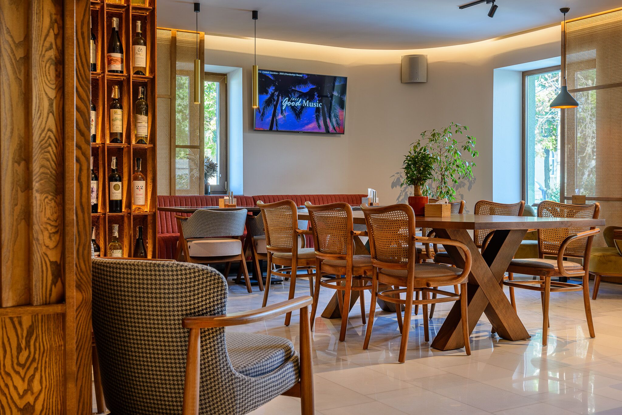 A dining area with wooden furniture, a television displaying a Christmas theme, and a bookshelf with wine bottles.