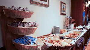 A buffet setup with multiple baskets of food items, including breads and pastries, arranged on a counter.