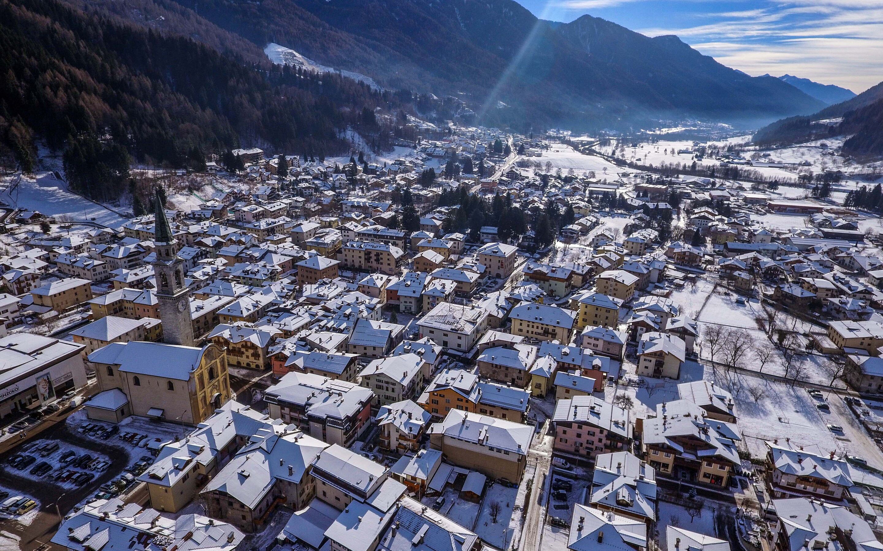 Une ville enneigée, avec une église imposante et une chaîne de montagnes en arrière-plan.