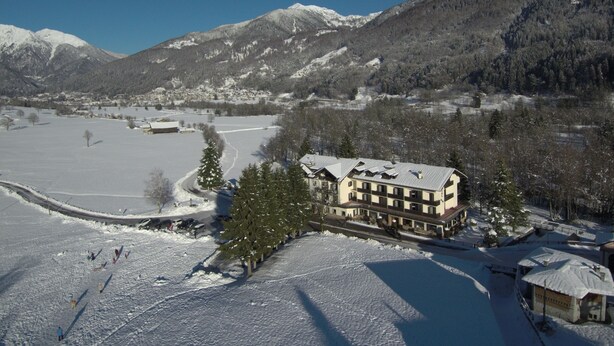 A large building with multiple floors, surrounded by snow-covered fields and mountains.