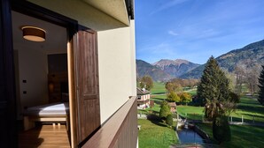 Un balcón con una cama de madera y vistas a un paisaje verde con montañas.