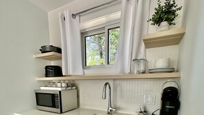 Een moderne keuken met een inbouwvaatwasser, een magnetron, een spoelbak en een raam met gordijnen.