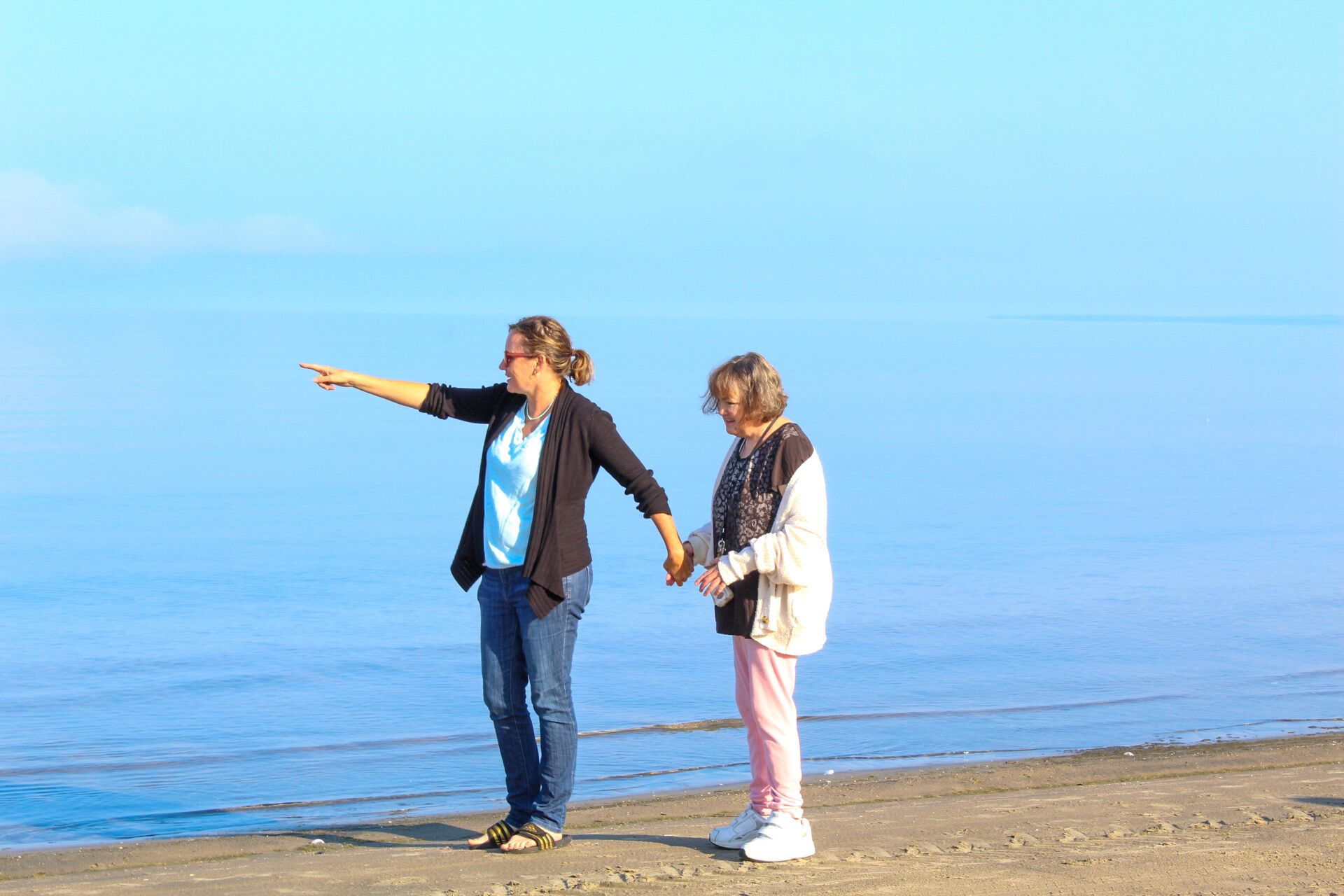 To personer på en strand med et roligt hav i baggrunden.