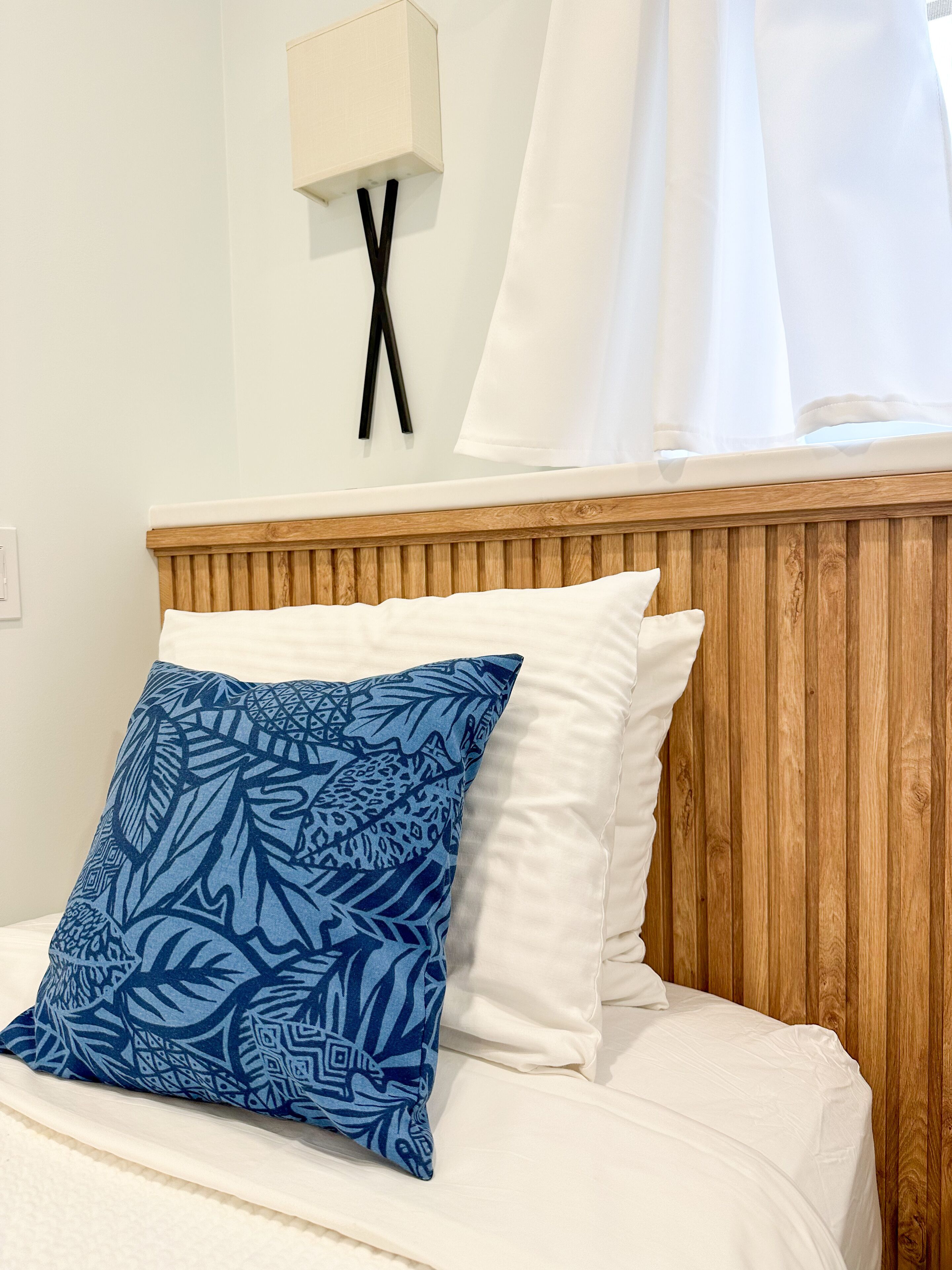 A bed with a white headboard, a blue patterned pillow, and a white pillow.