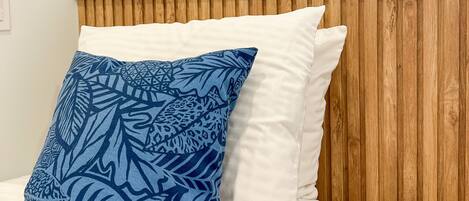 A bed with a white headboard, a blue patterned pillow, and a white pillow.