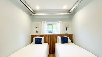 Habitación doble con dos camas, una ventana y una lámpara en el techo.