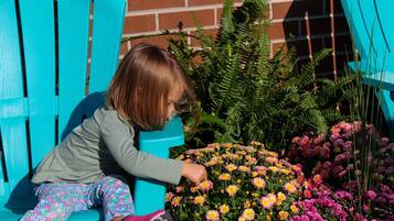 A child sitting on a blue bench next to a garden with various flowers.