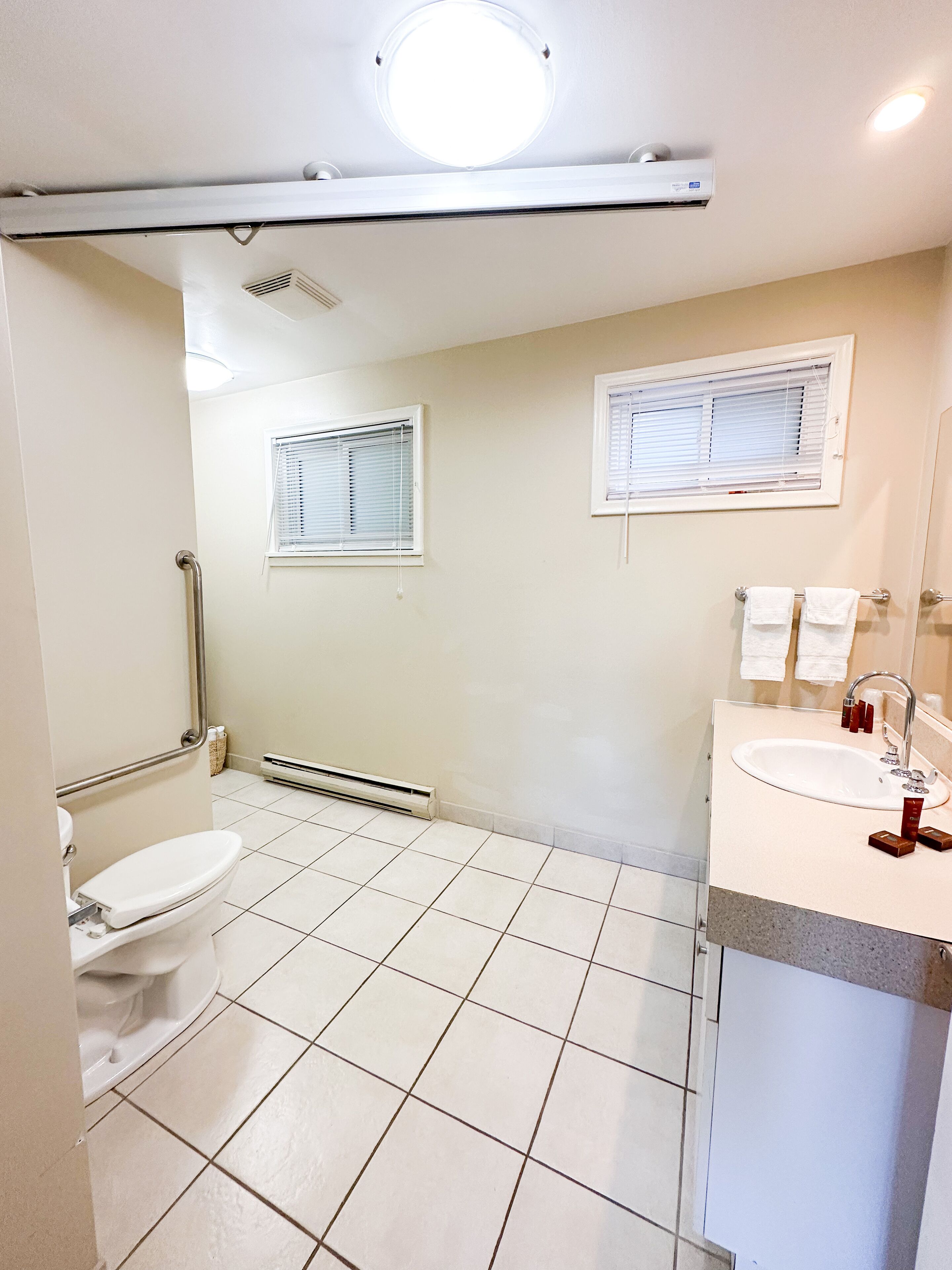 A bathroom with a toilet, a sink, a mirror, and a window.