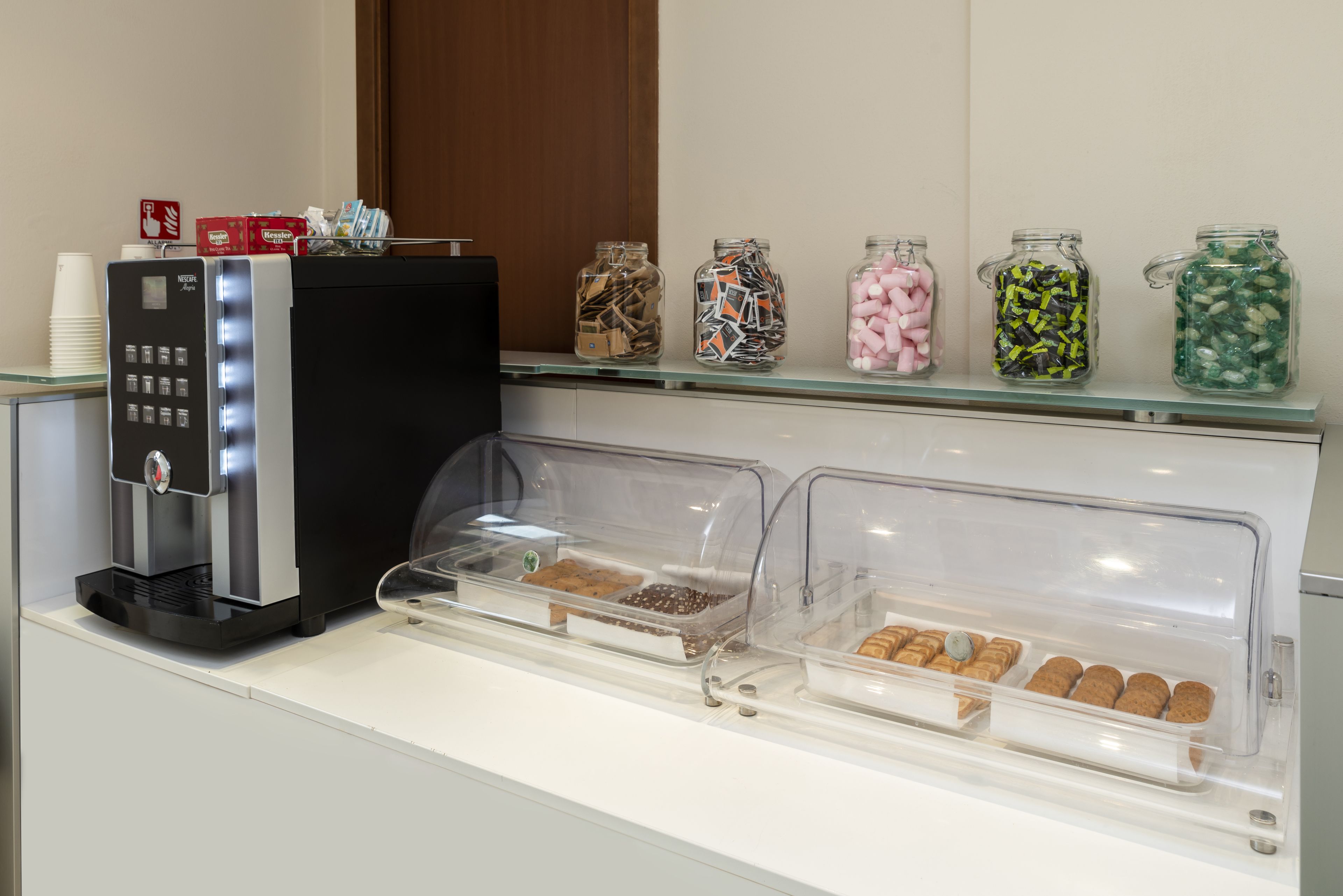 Un coin café équipé d’une machine à café, ainsi que d’une variété de collations et de bonbons présentés dans des bocaux.