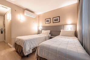 Una camera d'albergo con due letti, un climatizzatore, luci a parete e quadri appesi alle pareti.