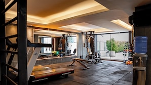 A gym with various exercise equipment, a water dispenser, and a large window with a view of greenery. - Laghetto Moinhos (Porto Alegre)