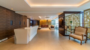 A modern hotel lobby with a reception desk, seating area, and decorative panels. - Laghetto Moinhos (Porto Alegre)