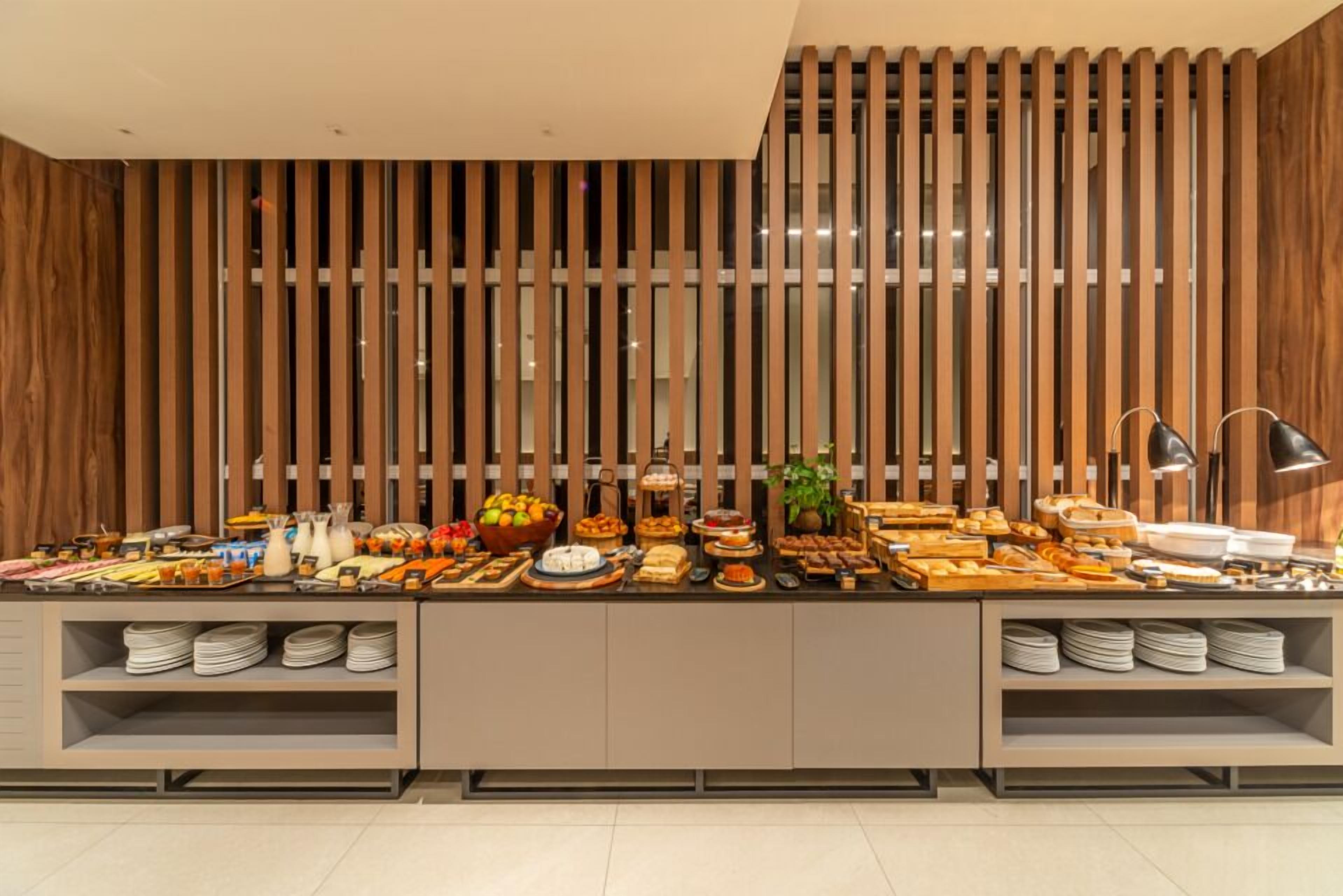 Disposição de buffet com diversos alimentos e design moderno de parede de madeira.