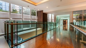 A modern interior with a glass railing, polished wooden floors, and large windows. - Laghetto Moinhos (Porto Alegre)