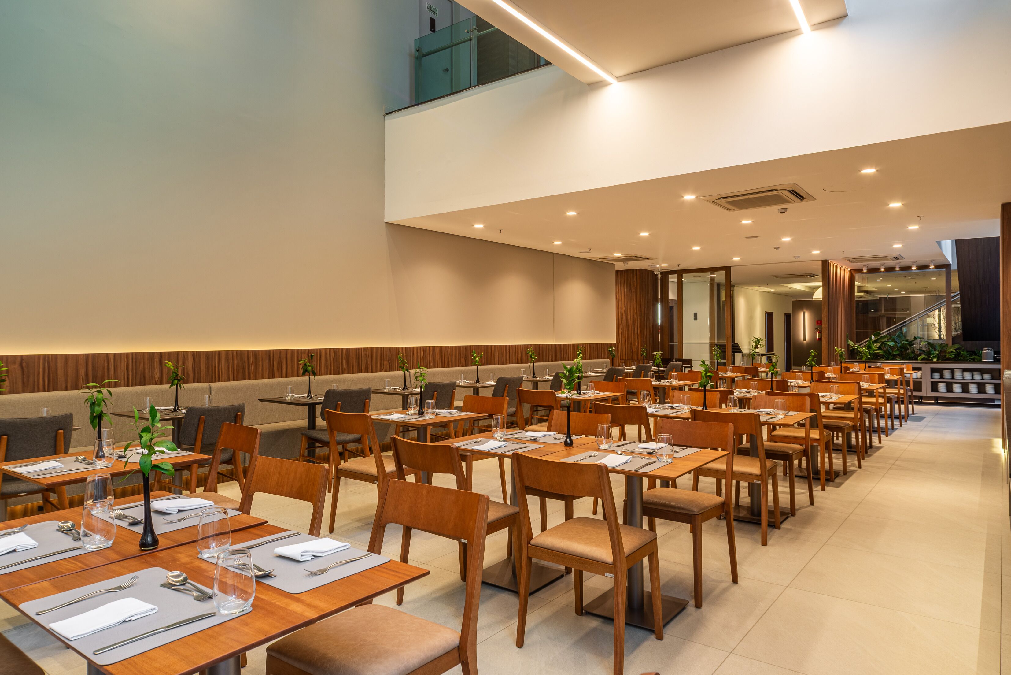 A modern dining area with multiple tables and chairs, a staircase, and a view of the interior.