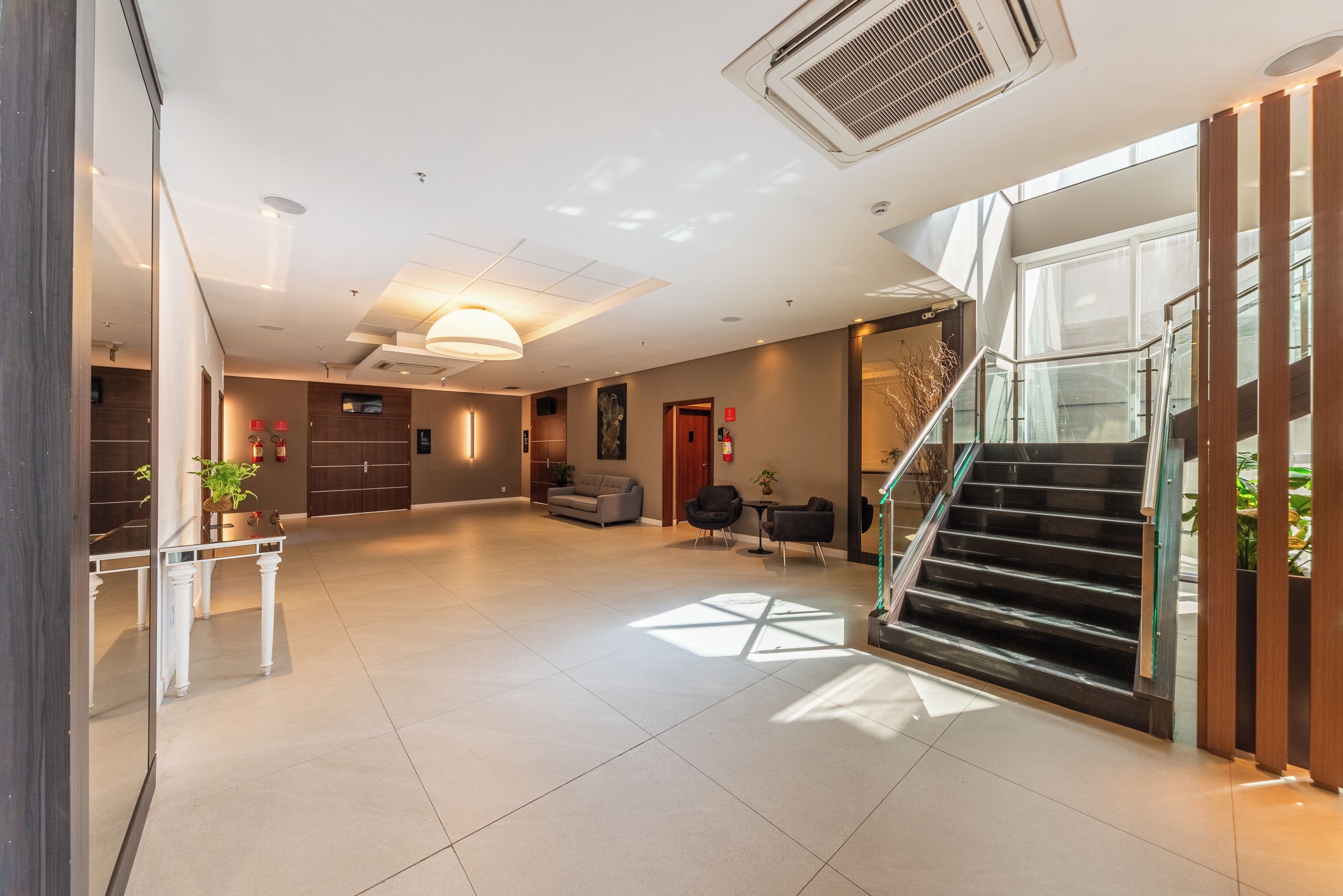 Um hall amplo com escada, área de estar e balcão de recepção.