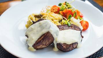 A plate with steak topped with sauce, rice, and a side salad.