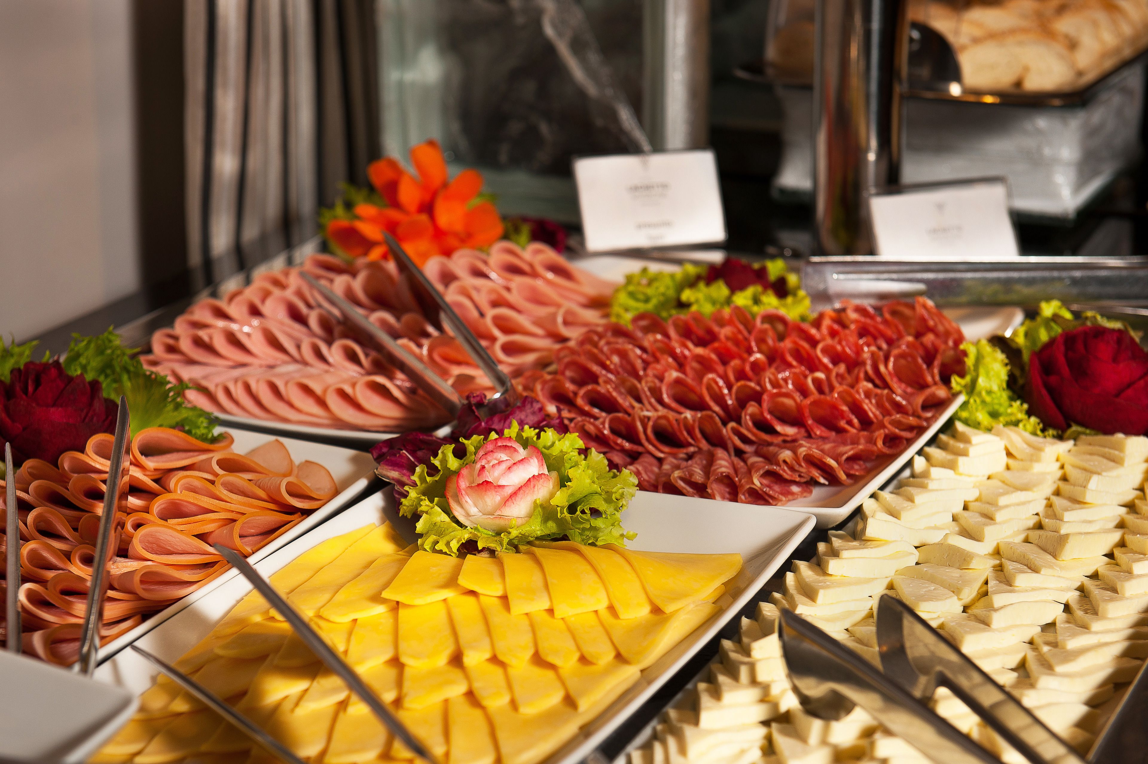 Un bufé con diversos alimentos, incluyendo carnes, quesos y verduras.