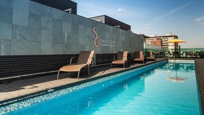 A swimming pool with lounge chairs and a wall with the text "SIR COLETOP BAR & STARTERS". - Laghetto Moinhos (Porto Alegre)
