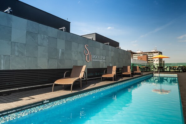 A swimming pool with lounge chairs and a wall with the text "SIR COLETOP BAR & STARTERS". - Laghetto Moinhos (Porto Alegre)