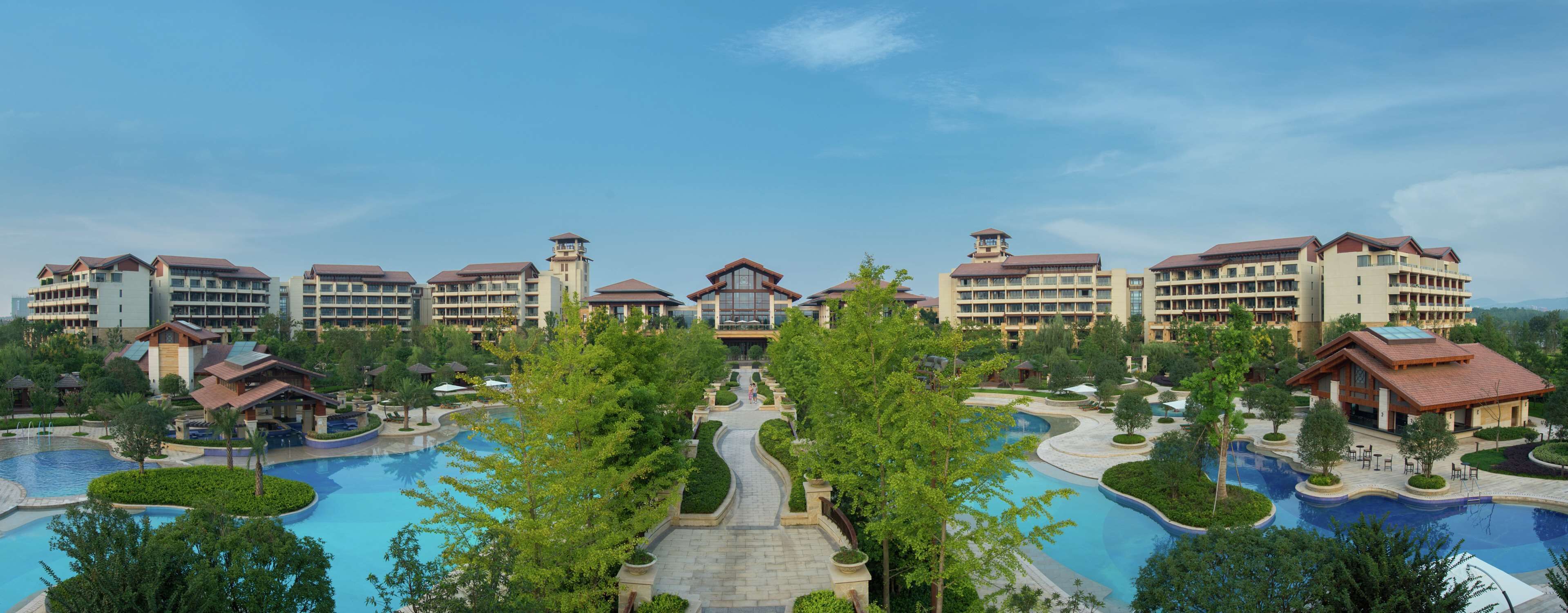 A resort with multiple buildings, a central pool area, and surrounding greenery.