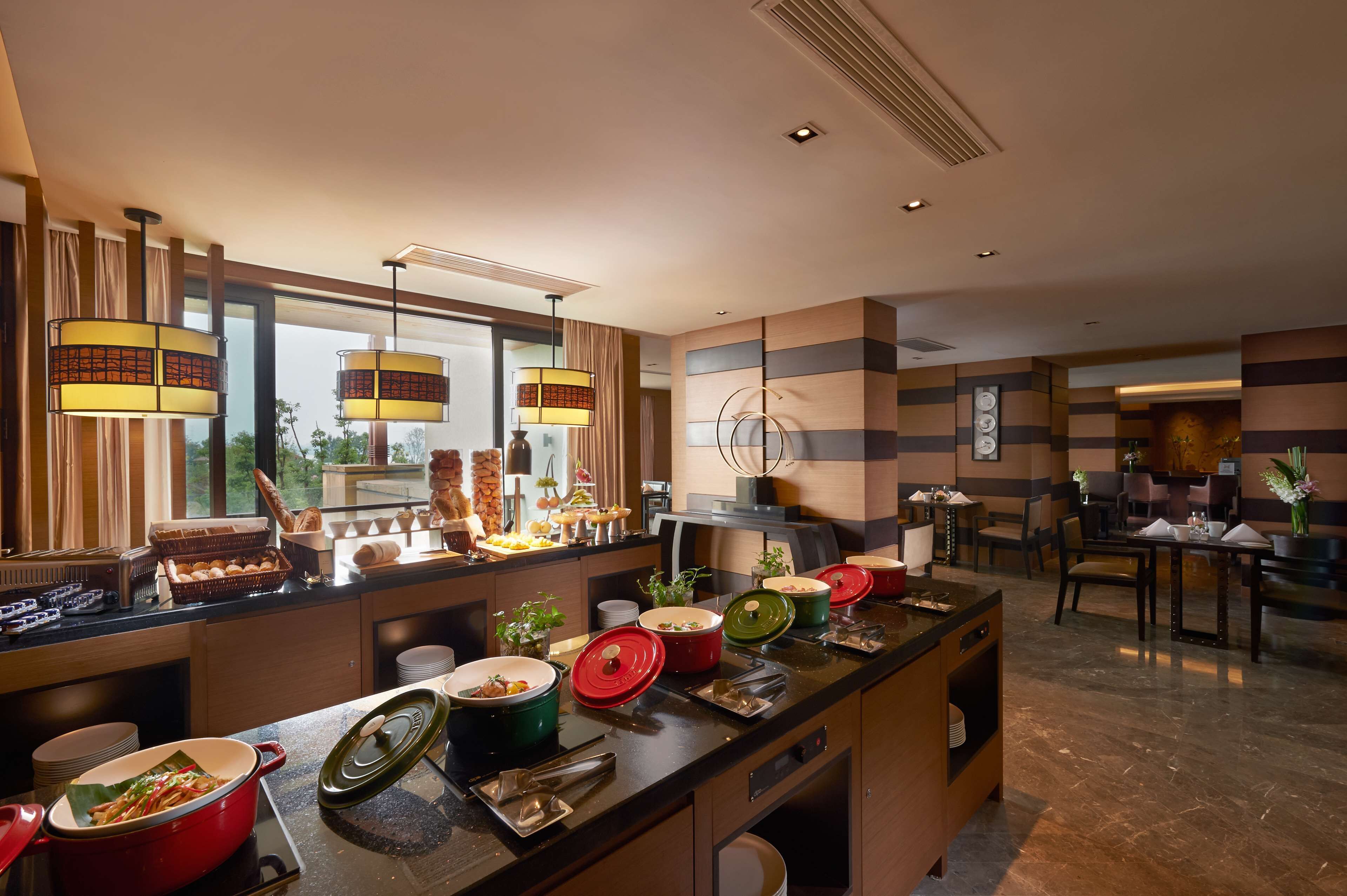 Een restaurantgedeelte in een hotel met een buffet, inclusief diverse gerechten en bestek.