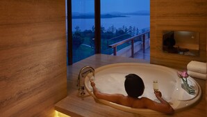 Un baño moderno con una bañera grande, vista al agua y paneles de madera.