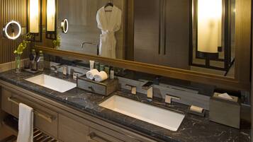 A modern bathroom with two sinks, a large mirror, and a robe hanging on the wall.