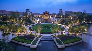 Un hotel grande con un patio central, múltiples fuentes y jardines bien cuidados.