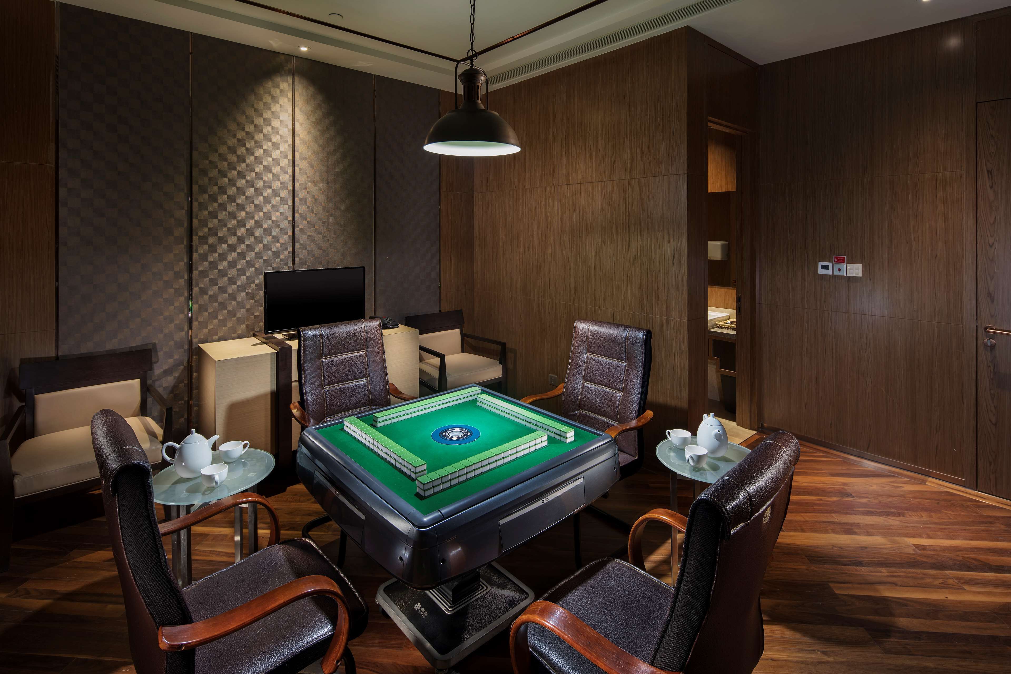 Une pièce comprenant une table de billard, des fauteuils en cuir, un téléviseur et un mur en bois.