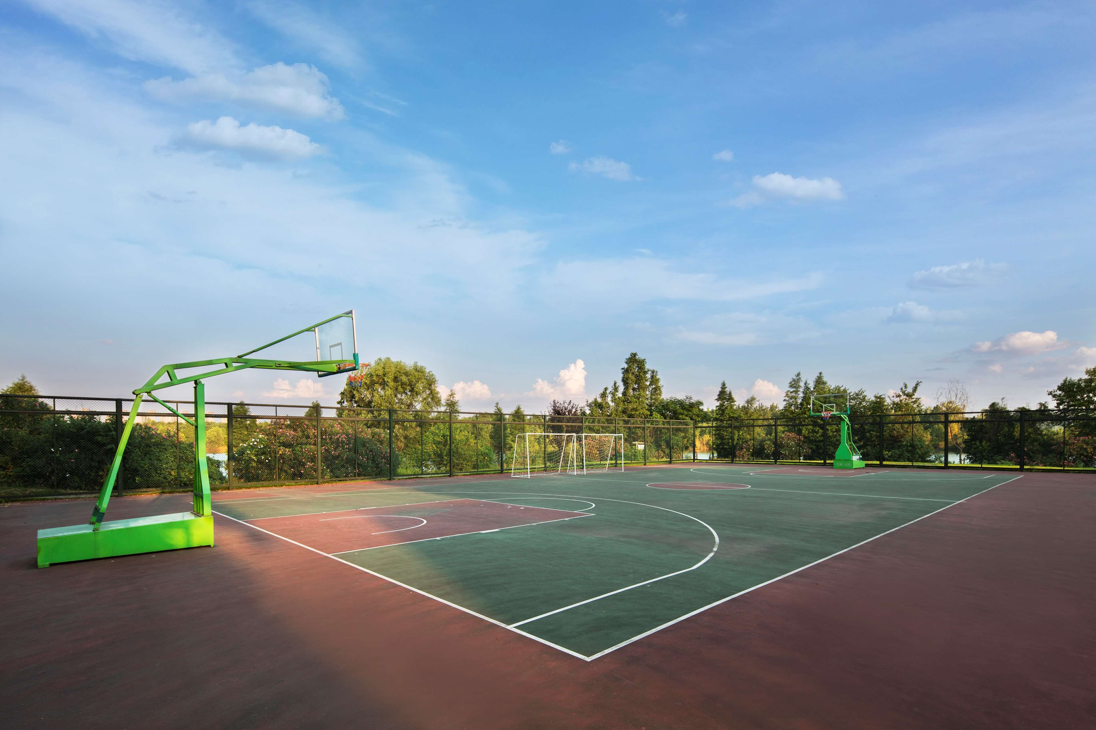 Una cancha de baloncesto al aire libre con un aro de baloncesto verde y una canasta.
