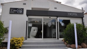 A hotel entrance with a modern facade, a large glass door, and a sign that reads "L'escalé HOTEL." - Hôtel L'Escale Coté Port (L'Île-Rousse)
