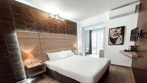 A modern bedroom with a large bed, wooden panel wall, and a view of the outdoors. - Hôtel L'Escale Coté Port (L'Île-Rousse)