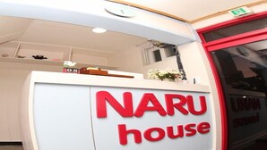 Un comptoir d’accueil avec une enseigne « NARU house » en lettres rouges.
