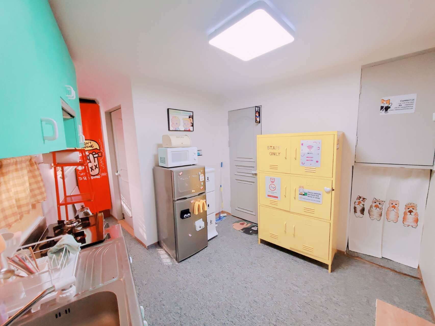 Une cuisine équipée d’un four à micro-ondes, d’un réfrigérateur, d’un meuble de rangement jaune et d’un autre four à micro-ondes placé sur le dessus du réfrigérateur.