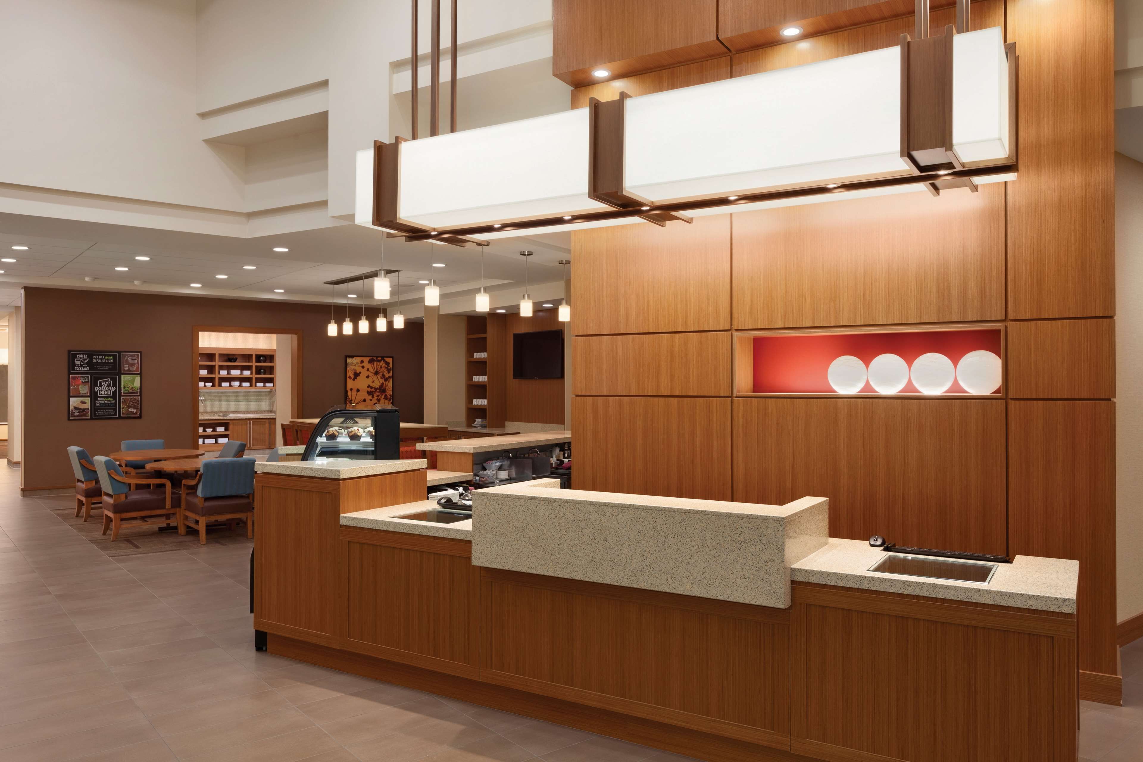 A modern kitchen with wooden cabinetry, a granite countertop, and pendant lighting.