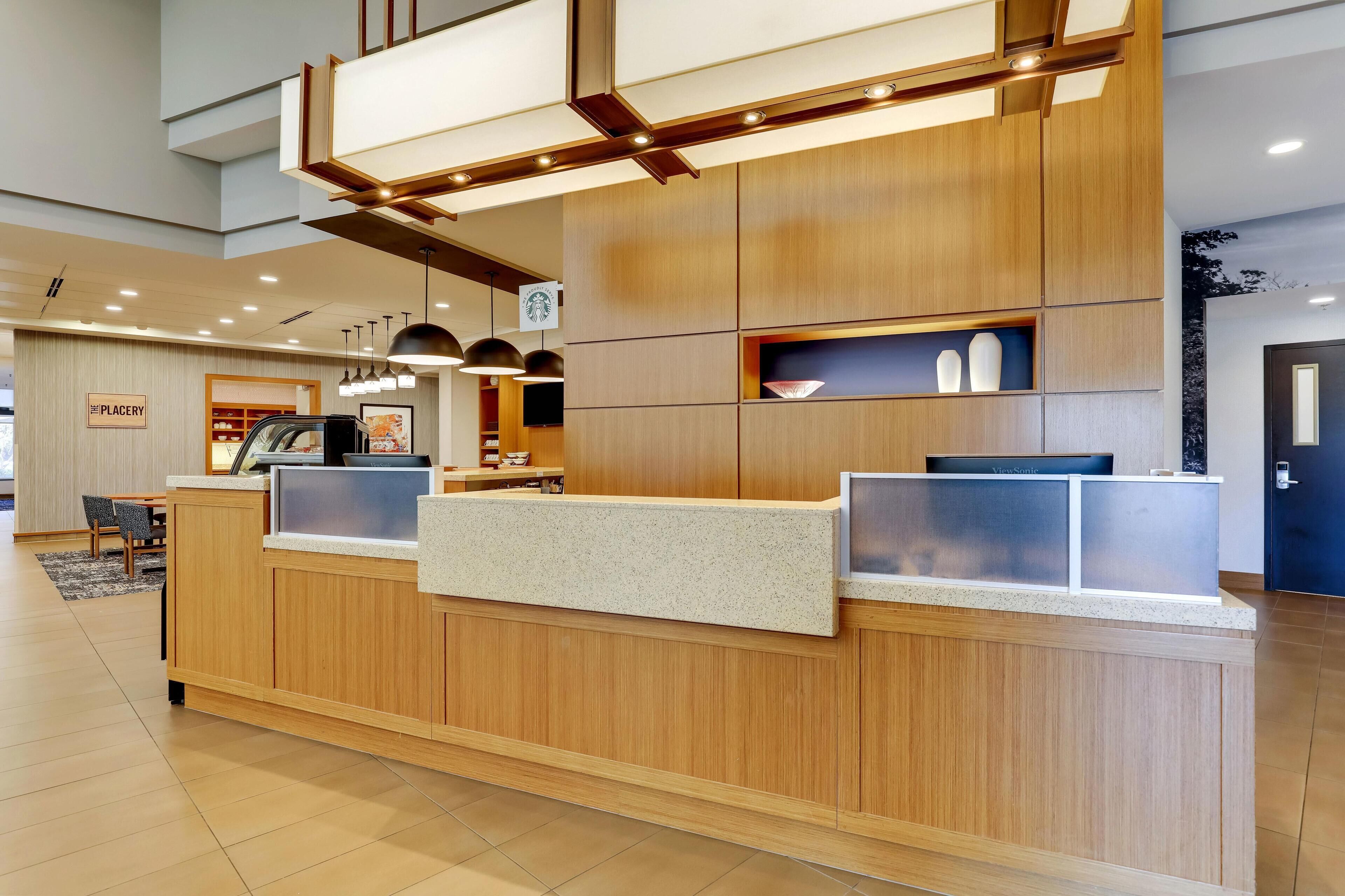 A reception desk with a wooden finish, a coffee machine, and a sign indicating a nearby placery.