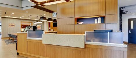 A reception desk with a wooden finish, a coffee machine, and a sign indicating a nearby placery.