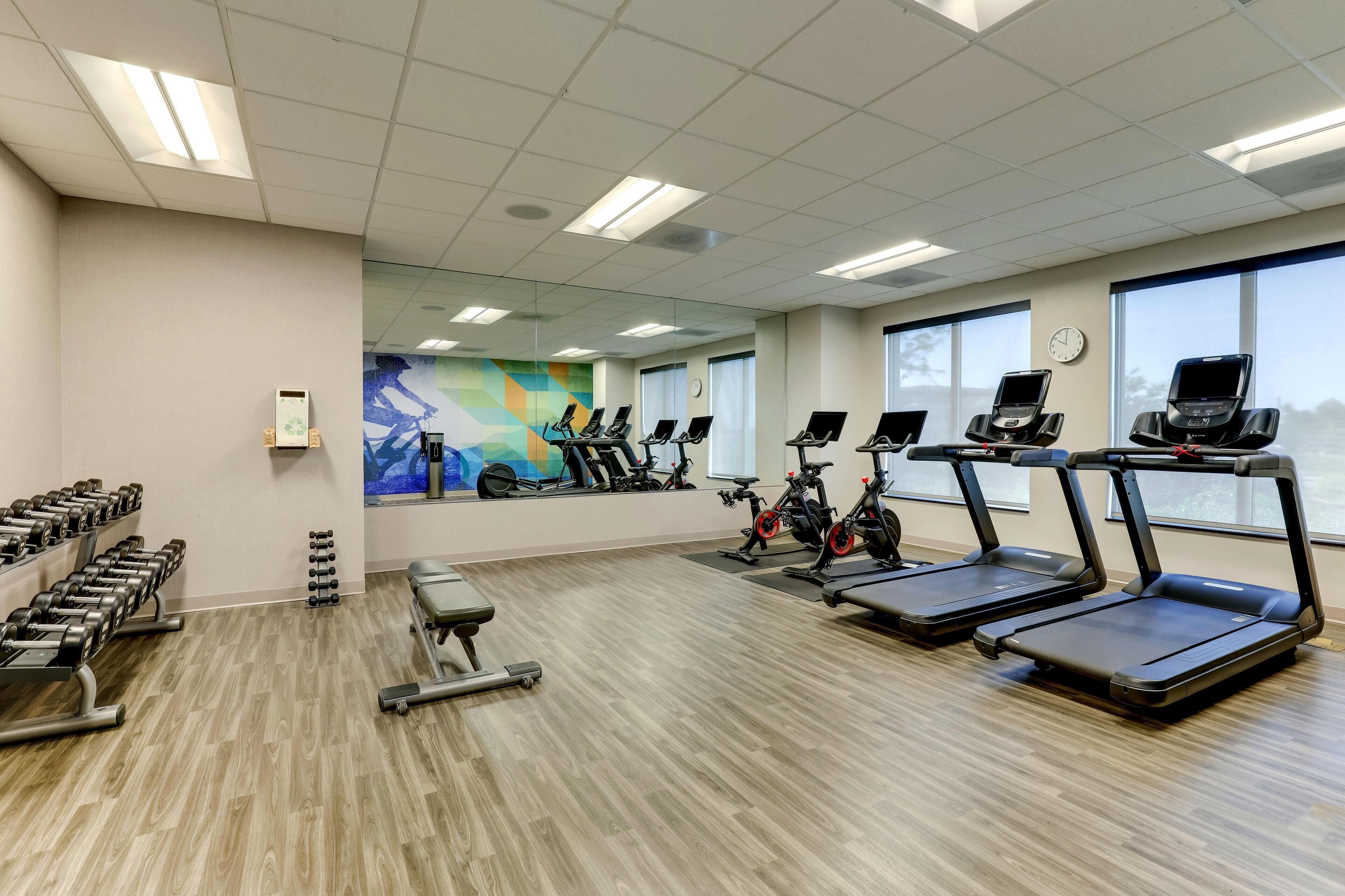 Une salle de sport équipée de tapis de course, de vélos d’appartement et d’haltères.
