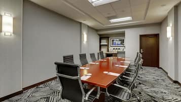 A conference room with a long table, chairs, and a framed picture on the wall.