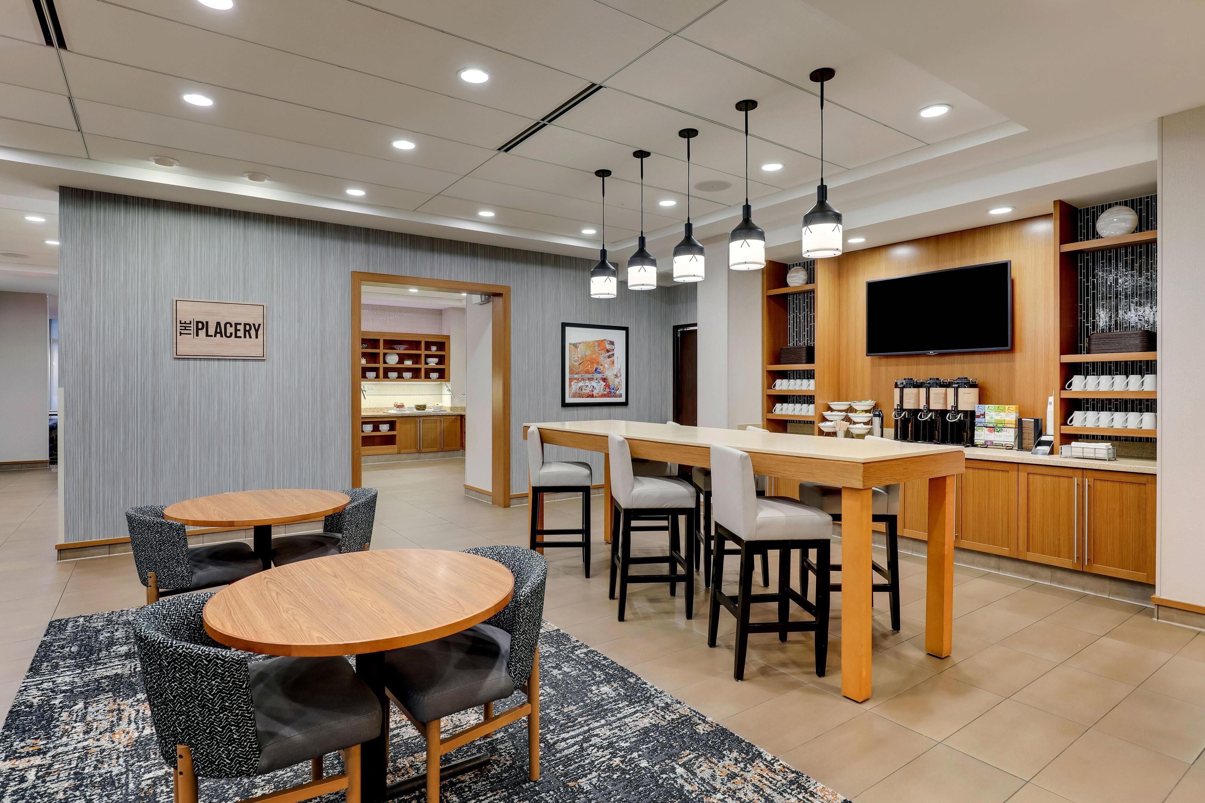 A hotel lobby with a bar area, seating, and a television.