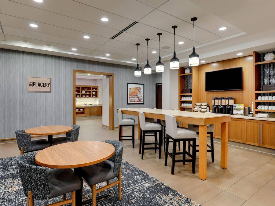 A hotel lobby with a bar area, seating, and a television.
