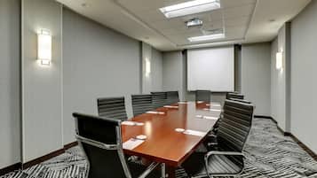 A conference room with a long table, black chairs, and a carpeted floor.