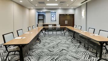 A conference room with a long table, chairs, and a patterned carpet.