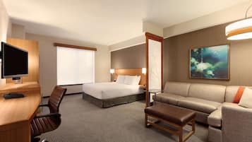 Una habitación de hotel con cama, sofá, escritorio con computadora y televisión.